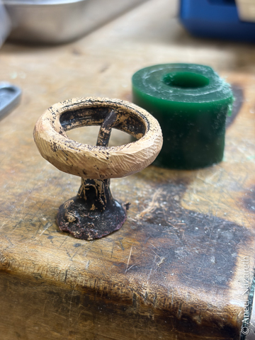 The ring in bronze. There's a conical "button" supporting it and sprues attaching the button to the inside of the ring